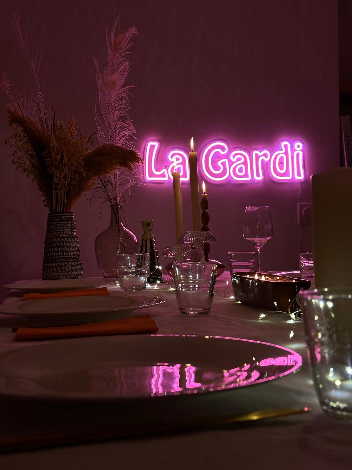 Néon LED rose La Gardi au-dessus d'une table dressée pour un dîner