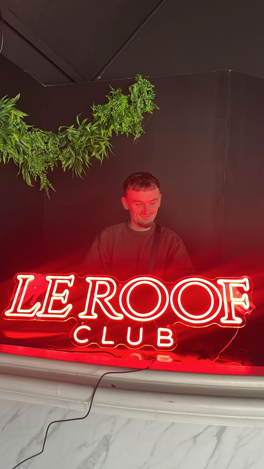 Néon LED rouge Le Roof Club derrière un DJ